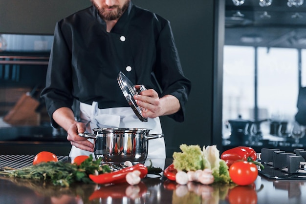 El joven chef profesional uniformado tiene un día ajetreado en la cocina