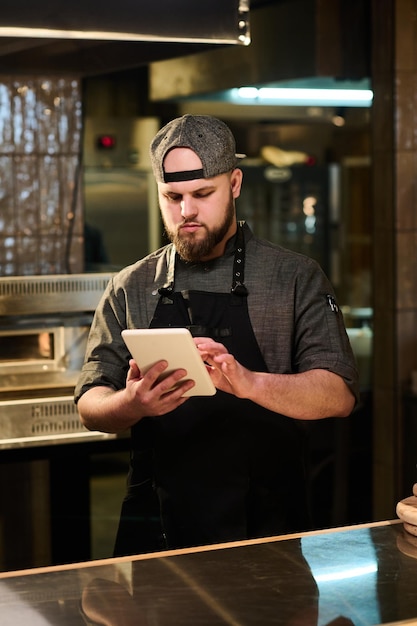 Joven chef de restaurante en busca de nuevas recetas en la cocina