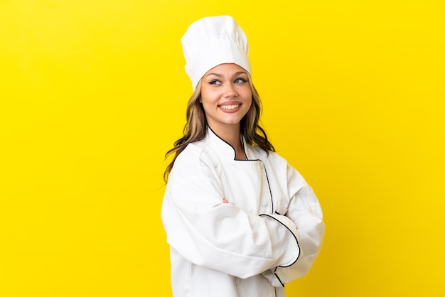 Joven chef rusa aislada de fondo amarillo con los brazos cruzados y feliz