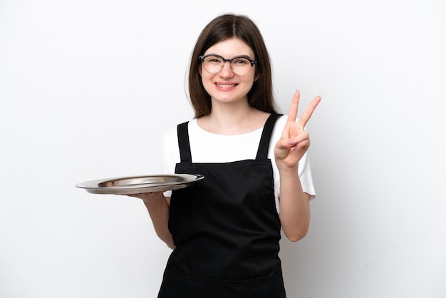 Joven chef rusa con bandeja aislada de fondo blanco sonriendo y mostrando el signo de la victoria