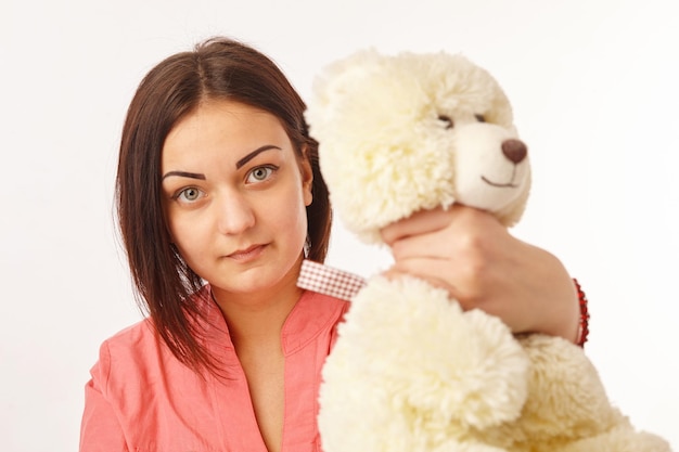 Joven chica bastante enojada estrangulando a un oso de peluche