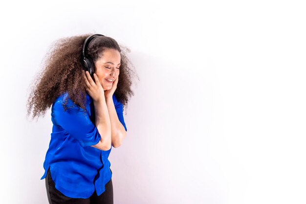 Joven chica de cabello afro escuchando música con auriculares en un fondo blanco aislado