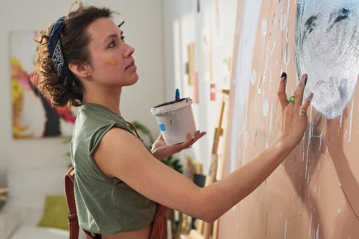 Foto joven chica creativa pintando una nueva obra maestra con las manos en un panel grande