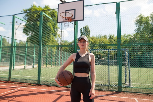 Joven chica deportiva con una pelota de baloncesto en la cancha de baloncestro al aire libre fin de semana activo