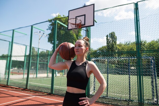 Joven chica deportiva con una pelota de baloncesto en la cancha de baloncestro al aire libre fin de semana activo