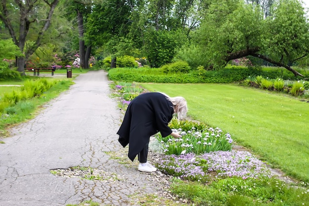 Joven chica rubia haciendo fotos en un parque de primavera