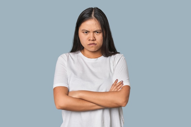 Foto una joven china aislada con la cara fruncida en el descontento mantiene los brazos cruzados