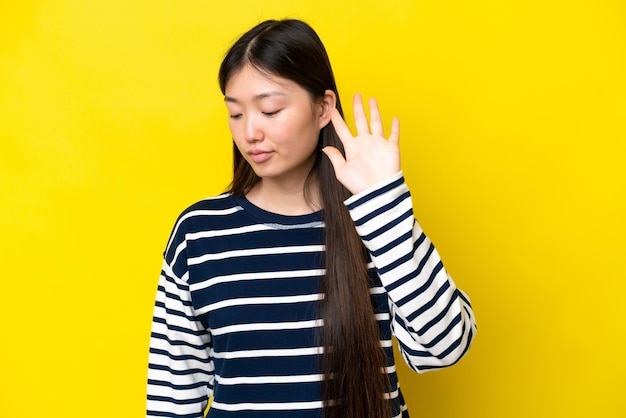 Foto joven china aislada de fondo amarillo haciendo un gesto de parada y decepcionada