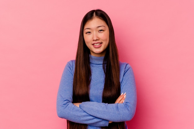 Foto joven china aislada en rosa que se siente segura, cruzando los brazos con determinación.