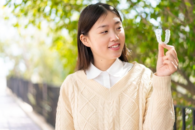 Joven china al aire libre sosteniendo aparatos ortopédicos invisibles