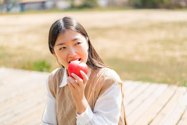 Joven china al aire libre sosteniendo una manzana