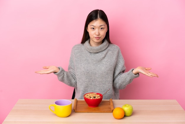 Joven China desayunando en una mesa con dudas