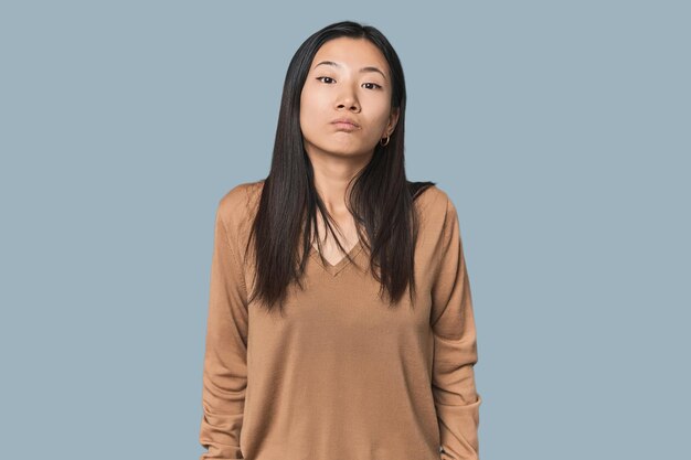 Foto una joven china en el estudio se encoge de hombros y abre los ojos confundidos.