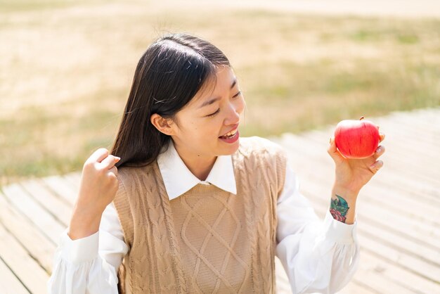 Joven china con una manzana al aire libre celebrando una victoria