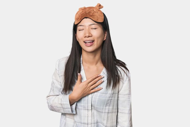 Foto una joven china con máscara de pijama se ríe en voz alta manteniendo la mano en el pecho