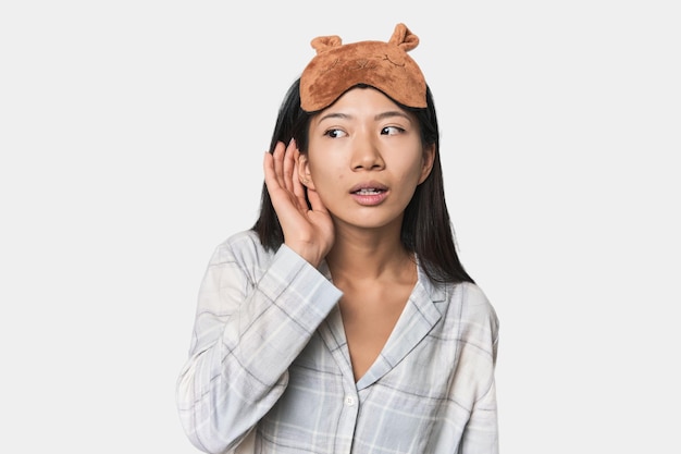 Foto una joven china con una máscara de pijama tratando de escuchar un chisme