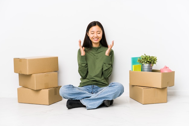 Joven china mudarse a un nuevo hogar alegre riendo mucho. Concepto de felicidad