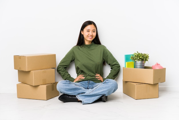 Joven china mudarse a un nuevo hogar seguro manteniendo las manos en las caderas.