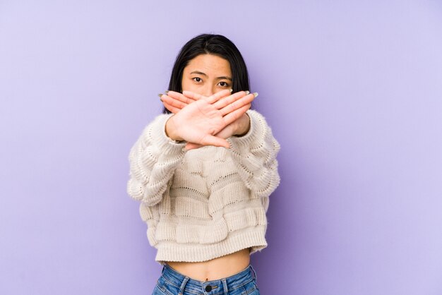 Joven china en una pared púrpura haciendo un gesto de negación