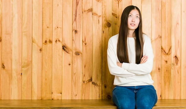 Joven china sentada en un lugar de madera cansado de una tarea repetitiva.