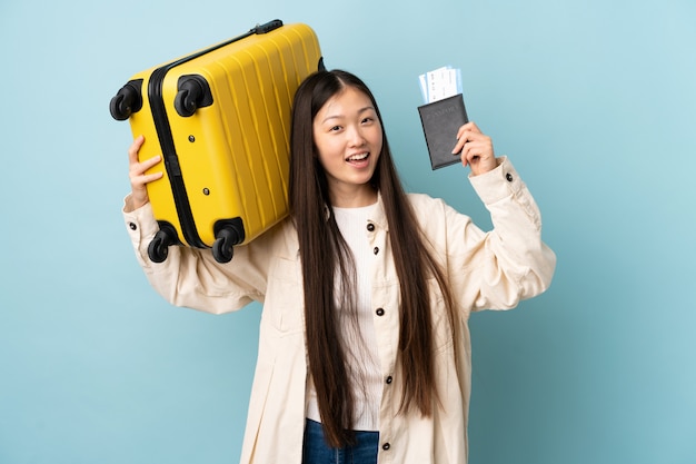 Joven china sobre aislado en vacaciones con maleta y pasaporte