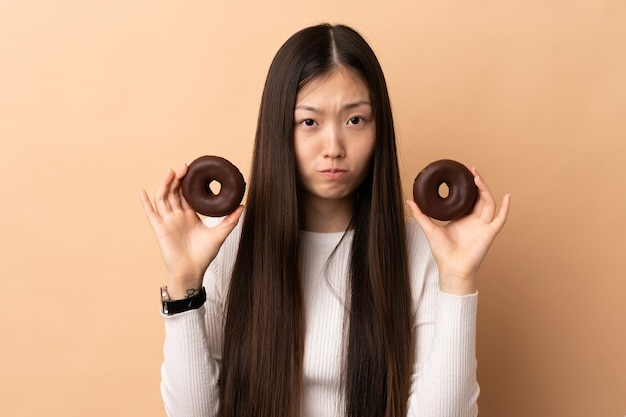 Joven china sosteniendo donas con expresión triste