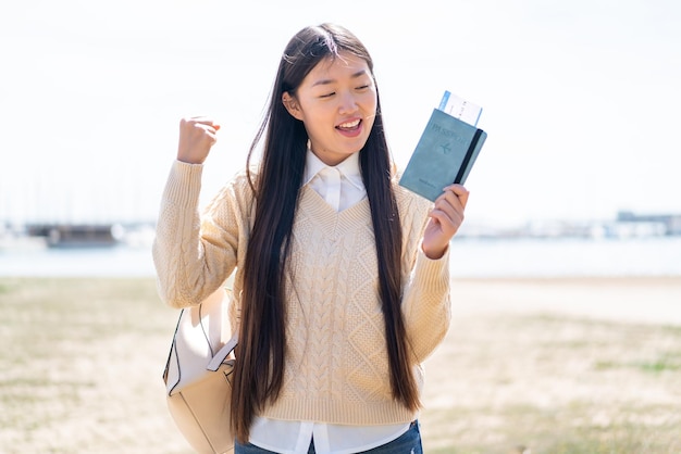 Joven china sosteniendo un pasaporte al aire libre celebrando una victoria