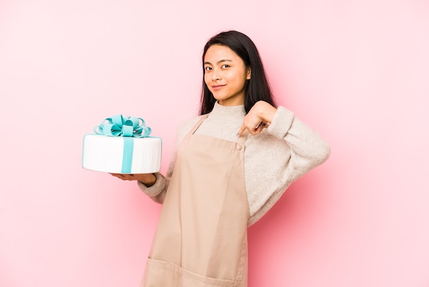 Joven China sosteniendo un pastel aislado soñando con lograr metas y propósitos