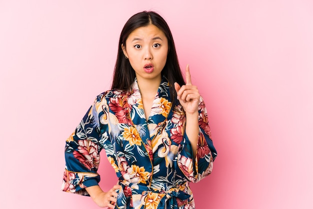 Joven China vistiendo un pijama kimono aislado teniendo una idea, concepto de inspiración.