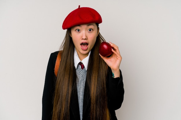 Joven China vistiendo un uniforme escolar aislado en la pared blanca