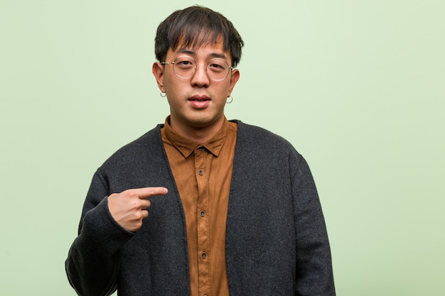 Joven chino contra una pared verde