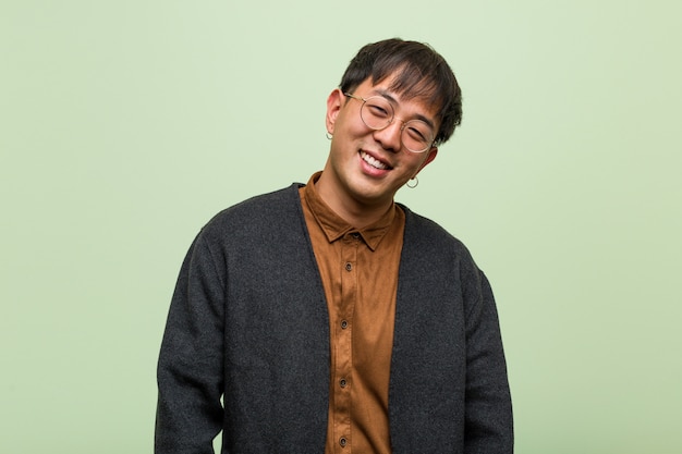 Joven chino con un estilo de ropa cool contra una pared verde