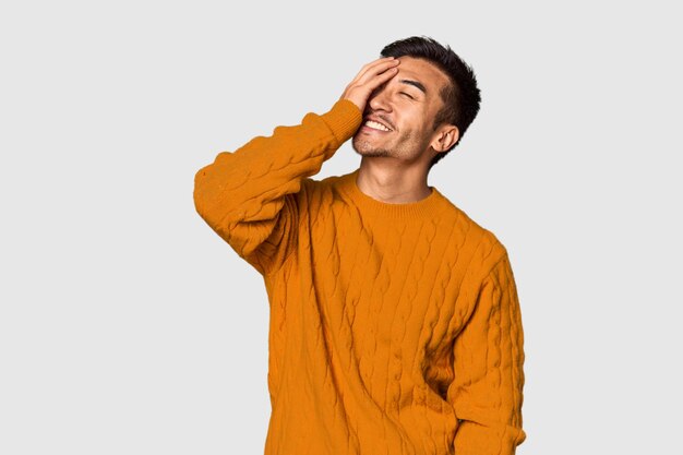 Joven chino en el fondo del estudio riendo feliz emoción natural despreocupada