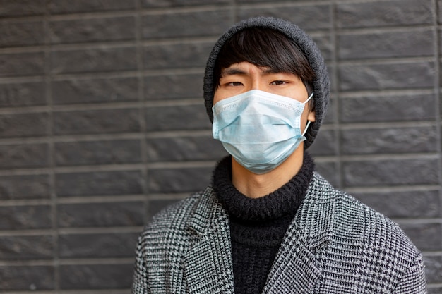 Joven chino con máscara facial contra 2019-nCov se ve molesto y miserable