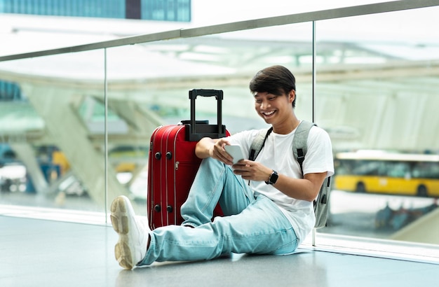 Joven chino usando teléfono celular mientras espera el vuelo