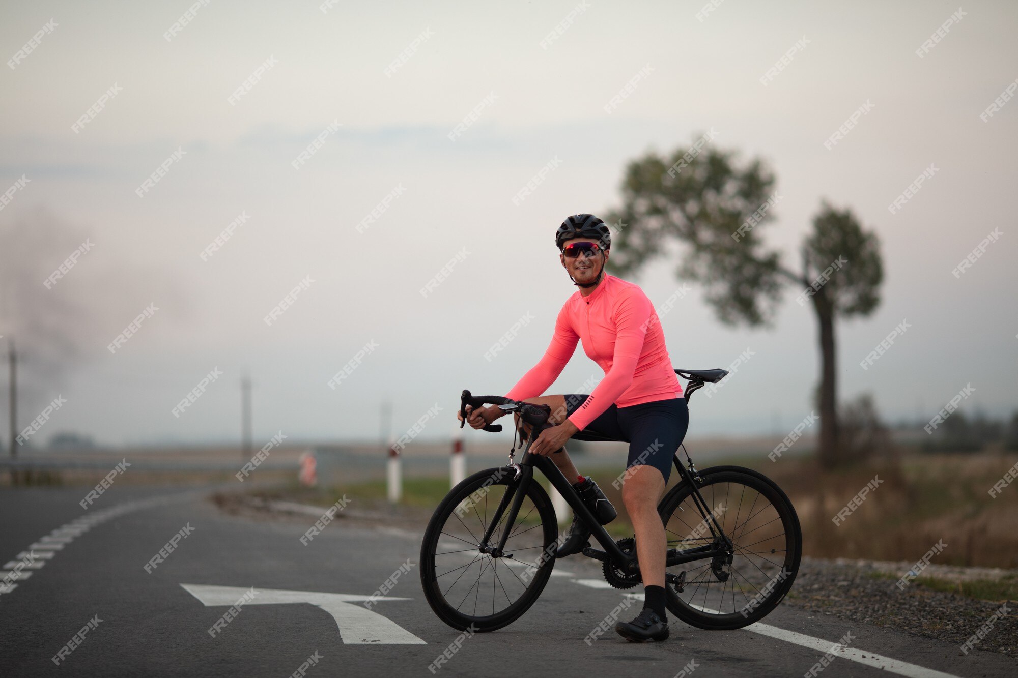 Hombre con casco y gafas sentado en bicicleta y sonriendo