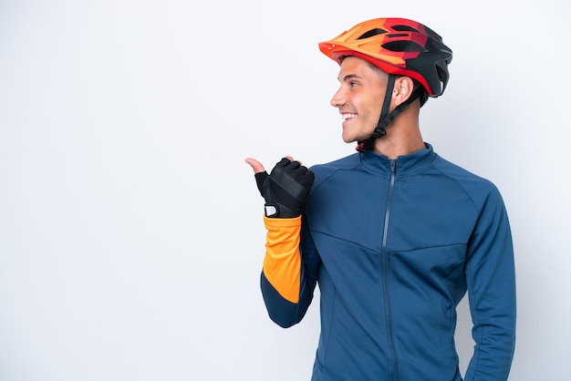 Joven ciclista hombre caucásico aislado sobre fondo blanco apuntando hacia un lado para presentar un producto