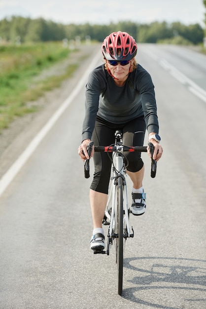 Joven ciclista en ropa deportiva de carreras en una carretera al aire libre