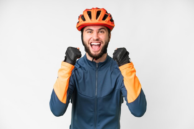 Joven ciclista sobre fondo blanco aislado celebrando una victoria en posición de ganador