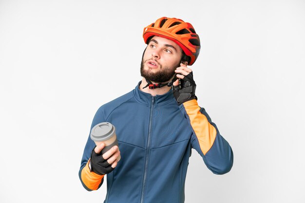 Foto joven ciclista sobre fondo blanco aislado sosteniendo café para llevar y un móvil