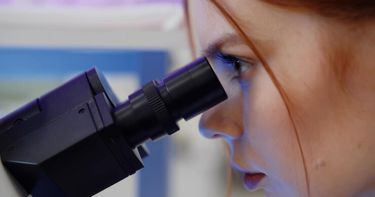 Joven científica que estudia una nueva sustancia o virus en el microscopio