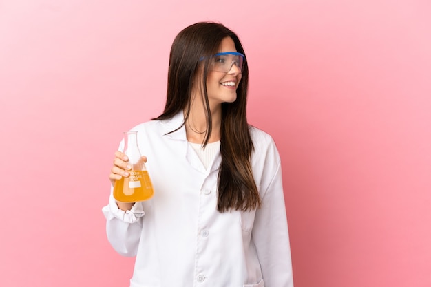 Joven científica sobre fondo rosa aislado mirando hacia el lado y sonriendo