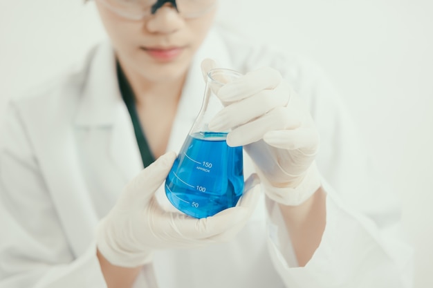 Joven científico asiático trabajando en el baño con tubos de ensayo y otros equipos para descubrir nuevas drogas