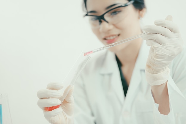 Joven científico asiático trabajando en el baño con tubos de ensayo y otros equipos para descubrir nuevas drogas