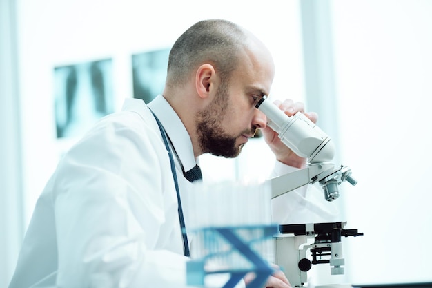 Joven científico estudiando las muestras obtenidas a través de un microscopio