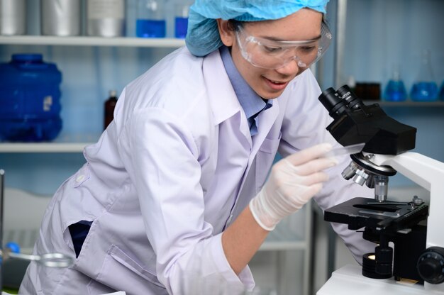 Joven científico mirando a través de un microscopio en un laboratorio