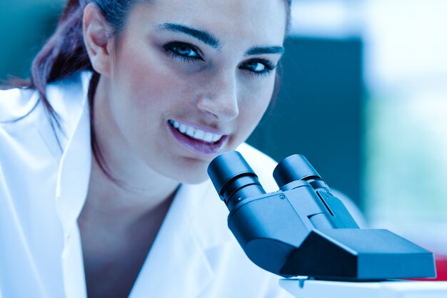 Joven científico posando con un microscopio