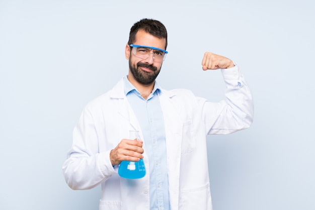 Foto joven científico sosteniendo frasco de laboratorio sobre pared aislada haciendo un gesto fuerte