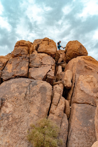 Joven en la cima de las rocas del árbol de joshua sintiéndose libre en el increíble paisaje