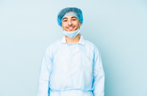 Foto joven cirujano hombre aislado contra una pared azul feliz, sonriente y alegre